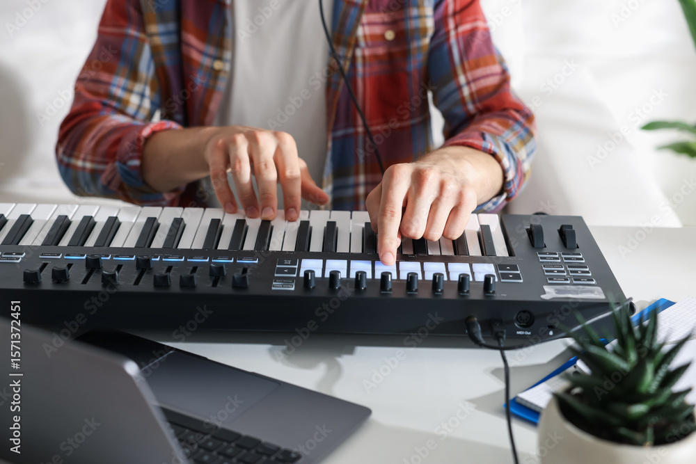Poster man working with midi keyboard at white table indoors, closeup