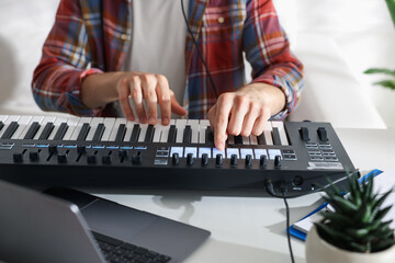 Man working with MIDI keyboard at white table indoors, closeup