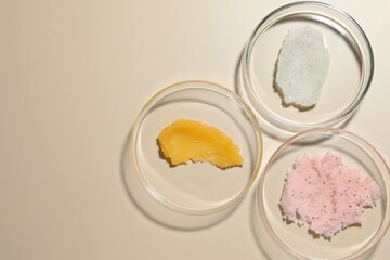 Different cosmetic products in Petri dishes on beige background, flat lay. Space for text