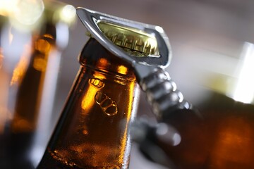 Opening bottle of beer on blurred grey background, closeup