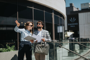 Two professionals collaborating outdoors in a modern urban setting with documents in hand
