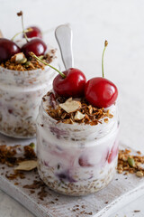 Healthy breakfast yogurt with multigrain granola, cherry,  and chocolate in glass jar, close up