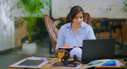 afghan asian gen z young adult woman lady girl sitting on chair use laptop desk look screen do work...