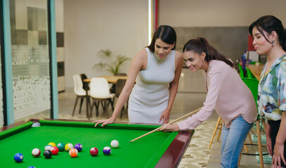 Indian happy young adult gen z woman lady hold cue stick hit ball play sport game on pool table...