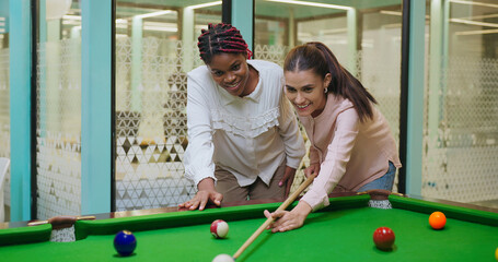 Indian happy young adult gen z woman lady hold cue stick hit ball play sport game on pool table...