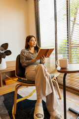 Woman enjoys book and music in modern abode.