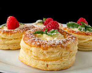Fresh raspberry pastry with cream and mint on dark background