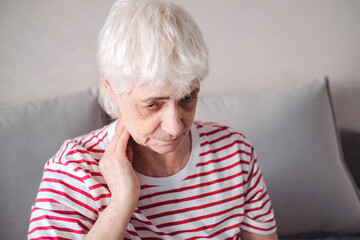 Old Age, Health Problem, Vision and People Concept - Close Up of Senior Woman Sitting on Sofa and Having Headache at Home. Elderly Woman With A Migraine