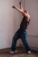 A forty year old sporty man in casual clothes dances in a room.