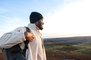 Hiker enjoying the sunset view from a high vantage point on a mountain in an expansive landscape