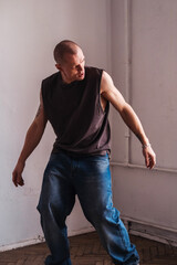 A sporty man in jeans dances a modern dance.