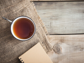 Elevated View of a Productive Workspace: Tea Cup, Notebook, and Burlap on Wooden Desk