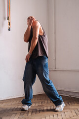 A sporty man in jeans dances a modern dance.