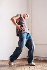 A sporty man in jeans dances a modern dance.