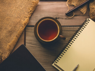 Elevated View of a Productive Workspace: Tea Cup, Notebook, and Burlap on Wooden Desk