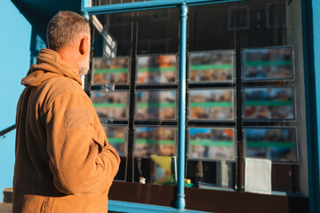 Elderly man admiring displayed art pieces in a vibrant urban setting during the warm afternoon light