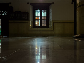 An interior shot of a room at night, with a window reflecting on the polished floor, creating a moody ambiance.