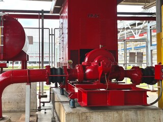 red fire hydrant. Bright red industrial fire pump system, used in emergency response within large-scale manufacturing facilities or warehouses.