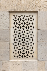 Intricately carved stonework featuring a geometric perforated window design