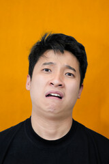 Young Man Expressing Displeasure Against Bright Orange Wall Background
