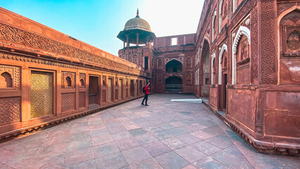 A man walking inside Agra Fort, India. Historic red sandstone walls showcasing intricate Mughal architecture.