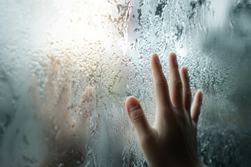 Hand Pressing On Dewy Glass Surface With Reflected Silhouette And Sunrise Glow Background. Foggy Window