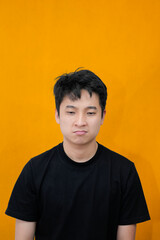 Young Man Expressing Displeasure Against Bright Orange Wall Background