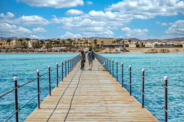 Tourists walking on a jetty in marsa alam, egypt, towards the beach resort