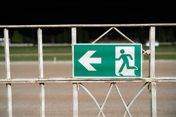 Emergency exit sign on metal fence outdoors