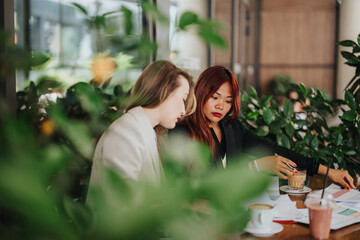 Business professionals working together at a table in a cafe with greenery around, showcasing team...