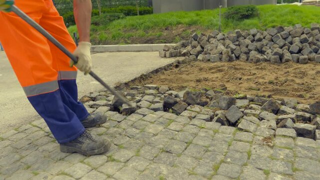Worker Removing Cobblestones During Road Maintenance on Urban Street &ndash; Close-Up