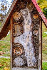Insect hotel showcasing diverse materials for shelter in a lush garden setting during daylight hours