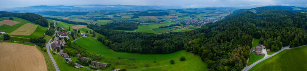 Aerial panoramic view of mountains and fields in Switzerland on a cloudy day in summer.