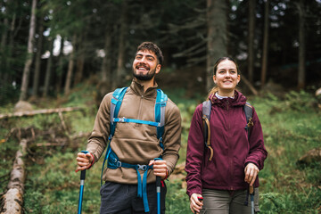 Young Adventurous Couple Hiking Through Mountain Forest with Full Gear