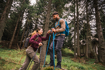 Supportive Couple Hiking in Mountain Forest – Man Helping Woman on Trail