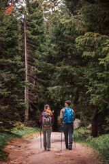 Young Couple Hiking Through Mountain Trail from Behind with Full Gear