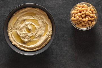 hummus with butter and chickpeas in bowls on dark table, top view