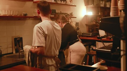 Female owner and male employee wiping plates with towels while standing behind the bar