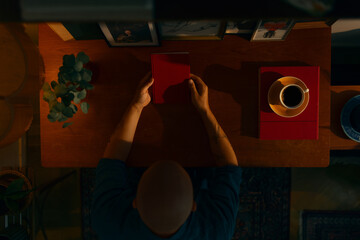 Portrait of a young caucasian man with a beard holding a book sitting in a cosy living room reading, top view.