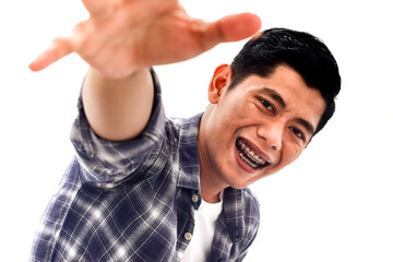 A young Asian man smiling with braces reaches out to the viewer in a friendly manner isolated on...