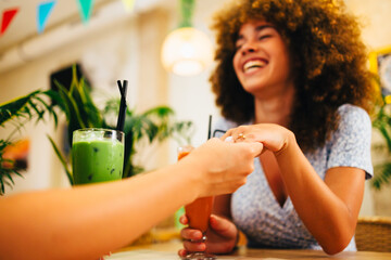 Woman showing off engagement ring to friend in cafe