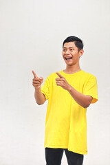 Enthusiastic Asian man in yellow shirt pointing with excitement and happiness towards the left side