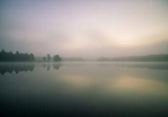 Fototapeta premium Serene Misty Lake at Sunrise A Peaceful Landscape Photograph