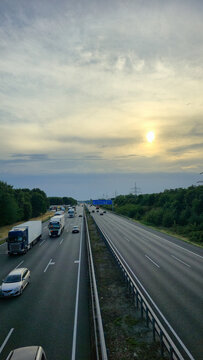 A beautiful and serene highway at sunset featuring vehicles in motion across the landscape