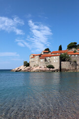 Historic island architecture with terracotta rooftops by the Adriatic Sea under a bright summer sky, Montenegro.