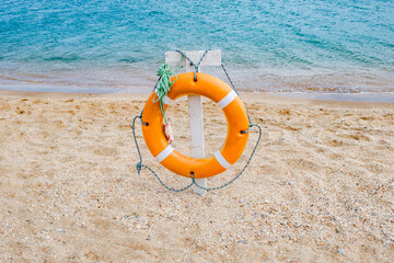 old orange lifebuoy on sandy beach