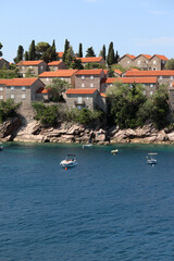 Picturesque seaside village with boats floating near the cliffs of Sveti Stefan, Montenegro