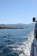 View of a coastal town from a moving boat with mountains in the background on a sunny day. Boka Kotorska Bay,  Bay of Kotor . Montenegro. Excursion around the bay.