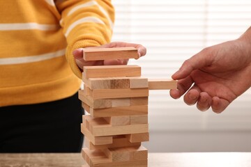 Lviv, Ukraine - December 08, 2023: People playing Jenga tower at table indoors, closeup