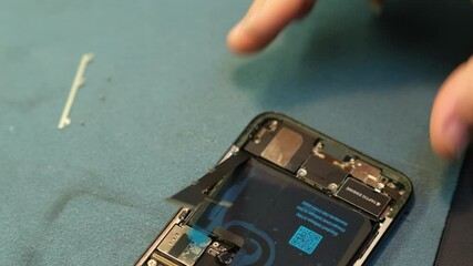 A technician skillfully disassembles a smartphone to troubleshoot and repair internal components using specialized tools and techniques in a repair shop.